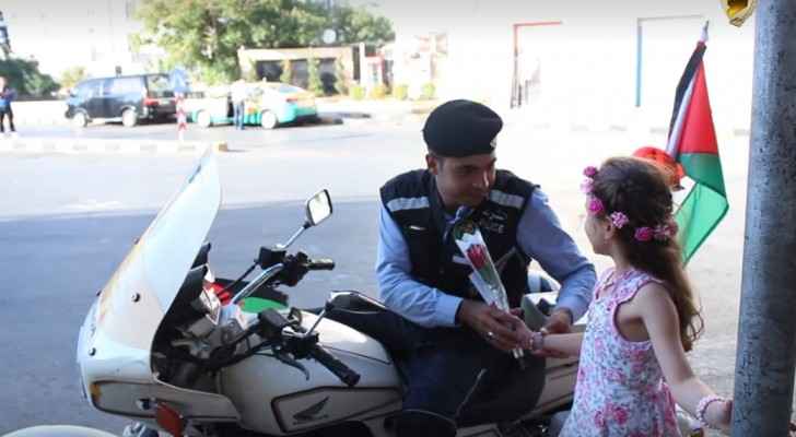 The little girl hands out a red rose to one of Amman's policemen. 