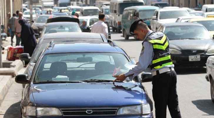 A policeman places a parking ticket on the windshield of a driver in Jordan. 