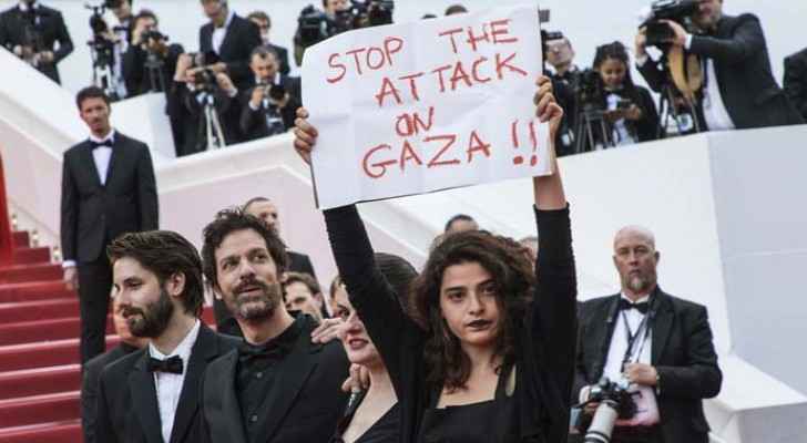 Lebanese actress Manal Issa holds a sign reading "Stop the Attack on Gaza" as she walks the famous red carpet in Cannes. (AP)