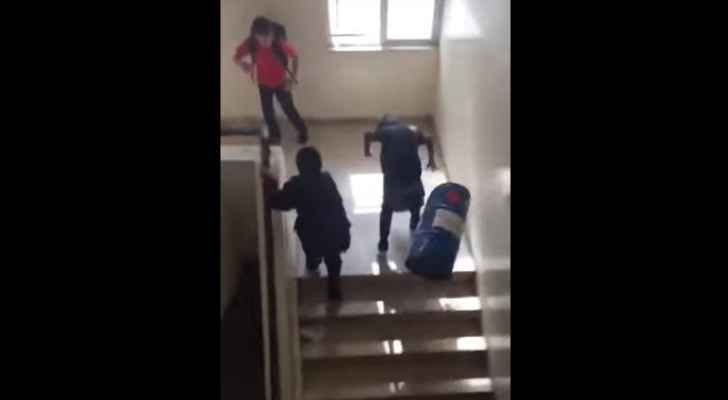 A recycling bin hits a student after it was thrown down the stairs by his peer. (YouTube)
