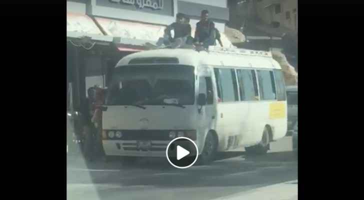 Students sit on top of a public transport bus in Zarqa. (Roya)