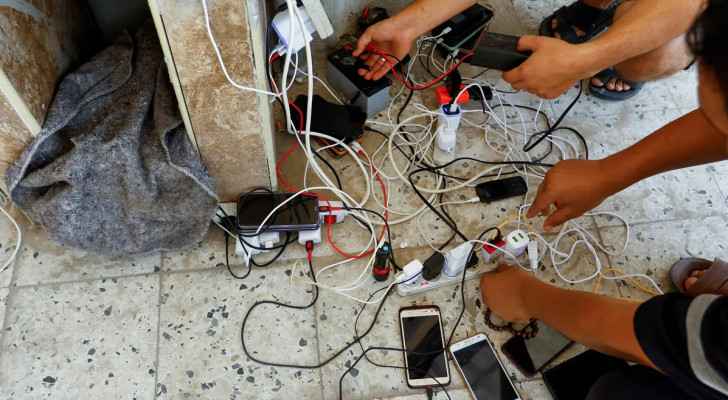 People charge phones from a point powered by solar panels in Khan Younis, Gaza (October, 14) (Photo: Ibraheem Abu Mustafa/Reuters)
