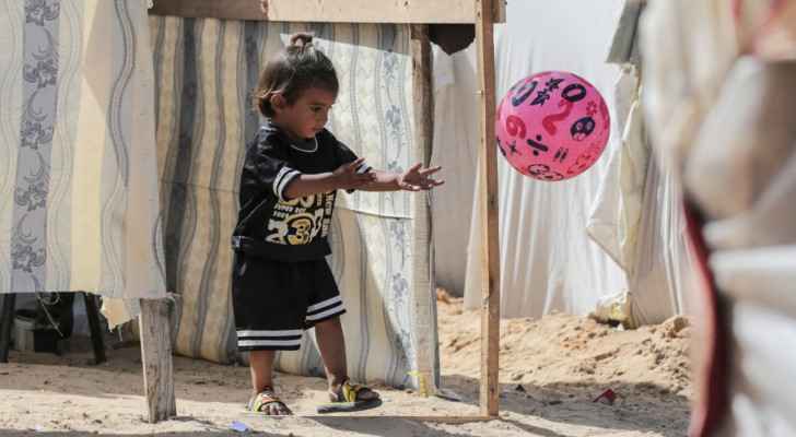 A Palestinian child plays with a ball amid tents at an area housing internally displaced people. (Nuseirat, central Gaza) (May 10, 2024) (Photo: AFP) 