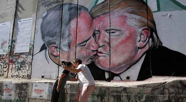 Tourists have their picture taken with the Trump-Netanyahu mural. (Reuters)