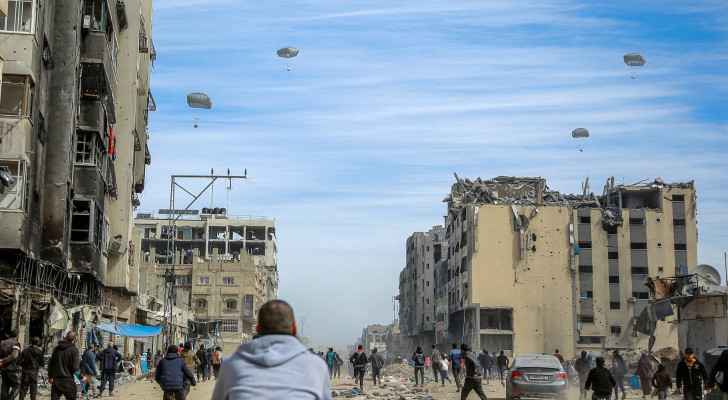 Palestinians run along a street as humanitarian aid is airdropped - AFP