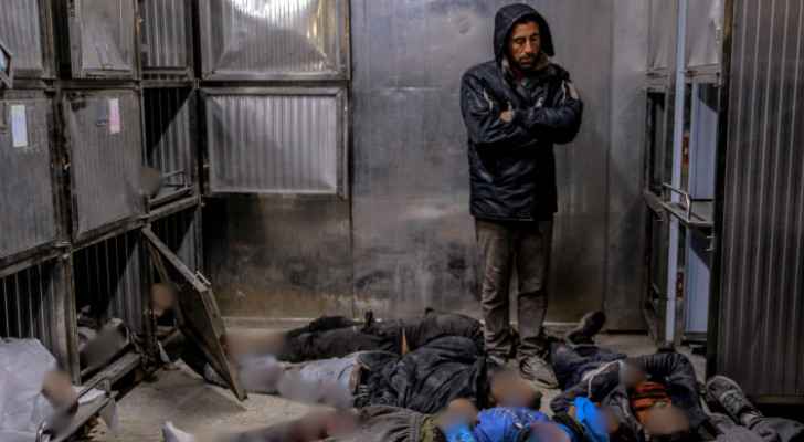 Palestinian man stands in a crowded morgue in a Gaza hospital, with bodies laid all over the floor. (File Photo) 