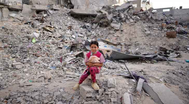 Palestinian girl dressed in new clothes sits amid the rubble of a destroyed building on the first day of Eid al-Adha in Khan Yunis. (June 16, 2024)