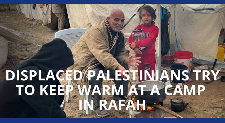 Displaced Palestinians try to keep warm at a camp in Rafah